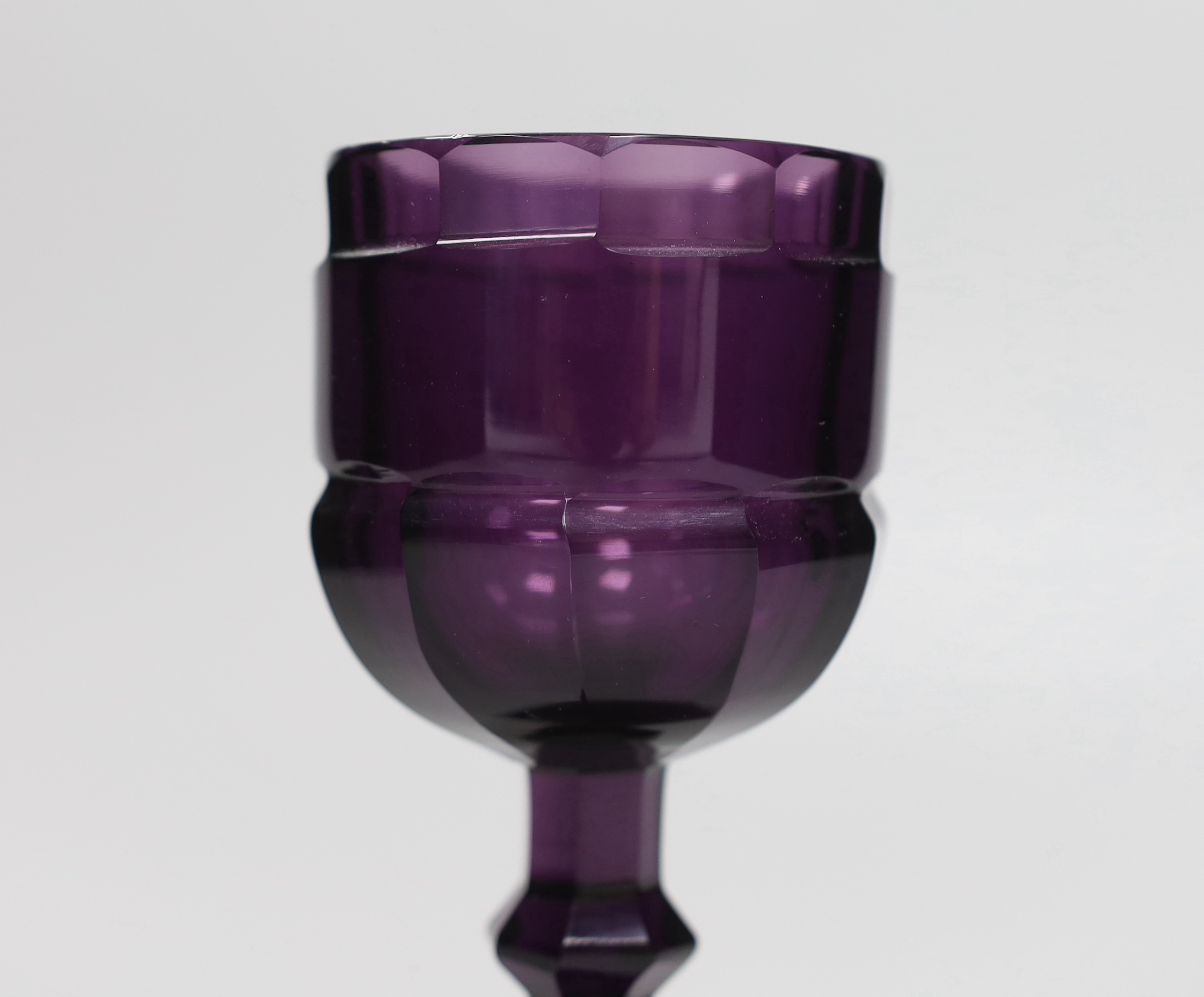 A Bohemian amethyst goblet, seemingly cut from a single piece of glass in a facetted form with a knopped stem cascading to a facetted foot with flat base and ground pontil, 17.5cm, weight 488 grams